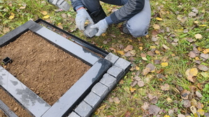 Стеклянный вертикальный памятник со скосом с гранитной вазой с цветами вид справа